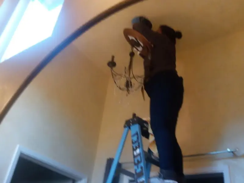 Electrician installing a chandelier in a Pasadena residence